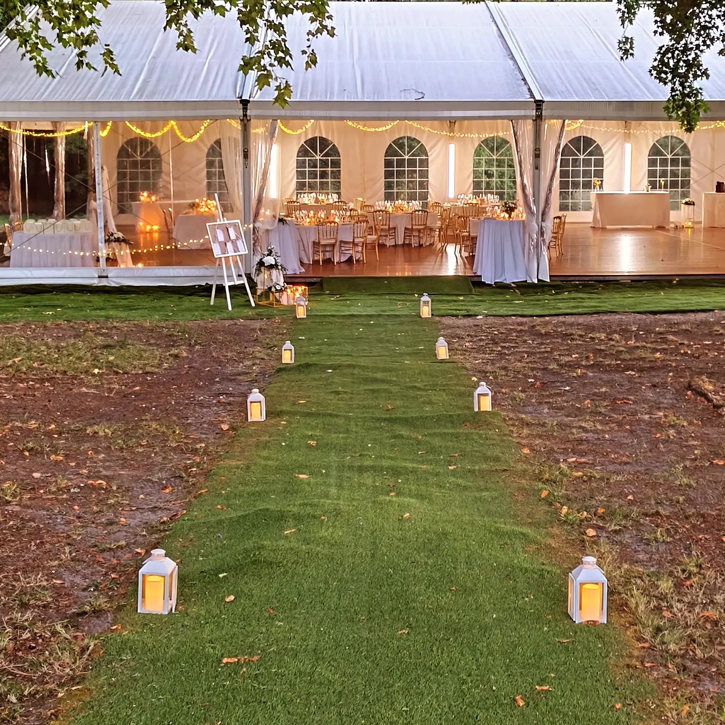 Allée de lanternes sur la pelouse, à la nuit tombée, jusqu'au chapiteau illuminé