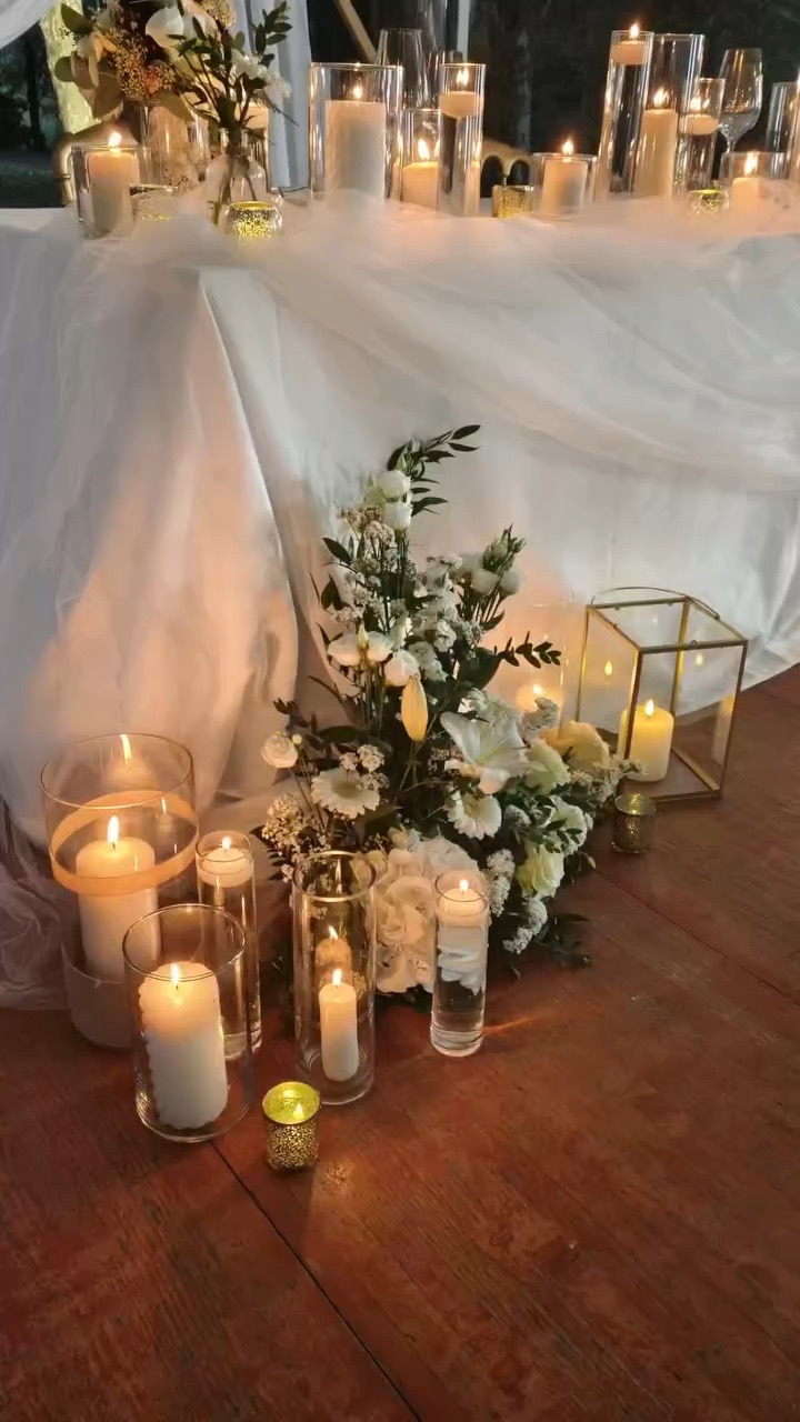 Bougies et fleurs blanches posées au sol, au pied de la table d'honneur