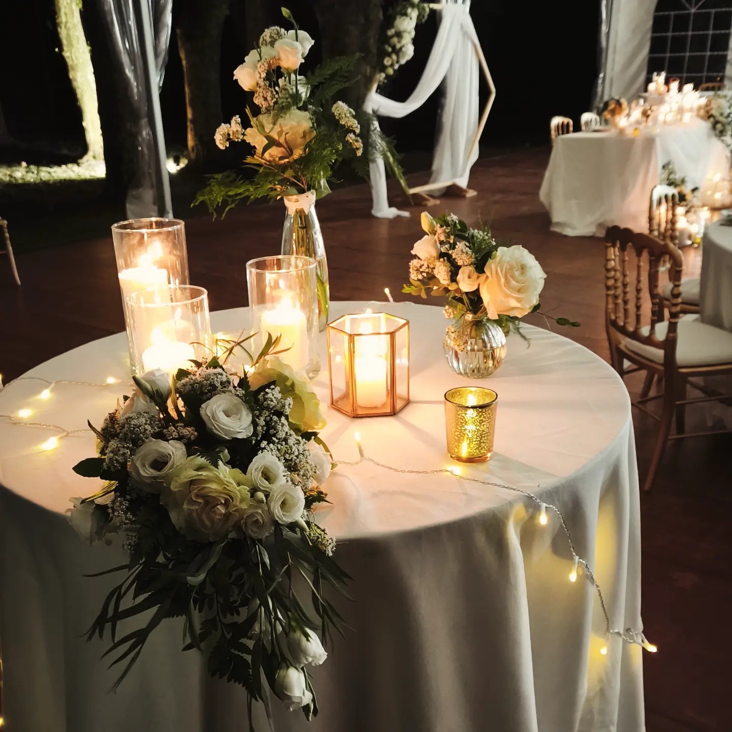 Centre de table : vase de fleurs blanches, lanterne dorée et bougies