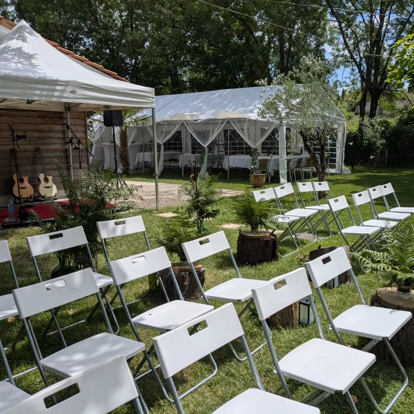 Le jardin des mariés prêt pour la cérémonie : chaises blanches, chapiteau et arbres