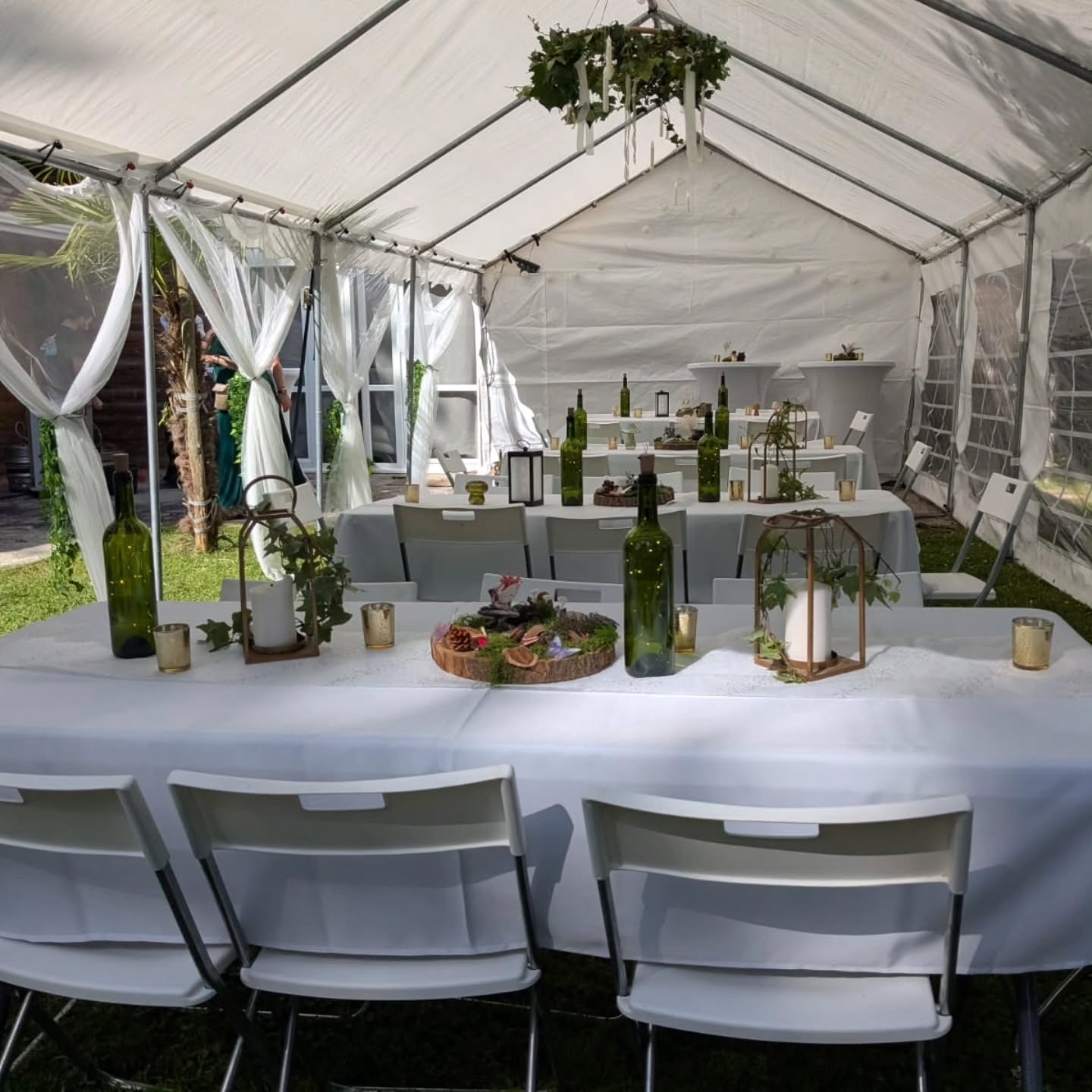 Sous le chapiteau : tables nappées de blanc, centres de table en rondins