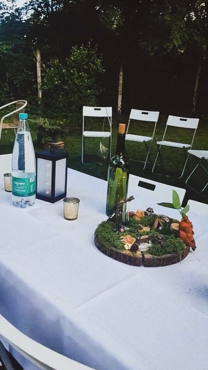 Table nappée de blanc dans le jardin, centre de table en rondin et lanterne