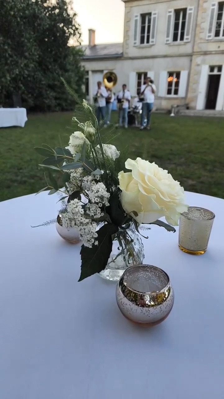 Rose blanche et photophores dorés sur une table haute du cocktail